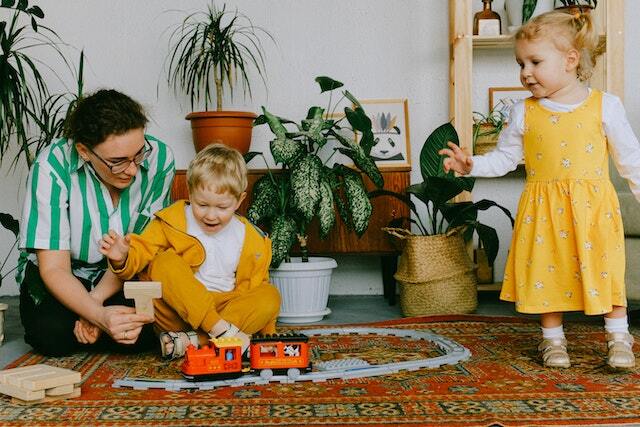 children playing with a toy train in the living room with a parent